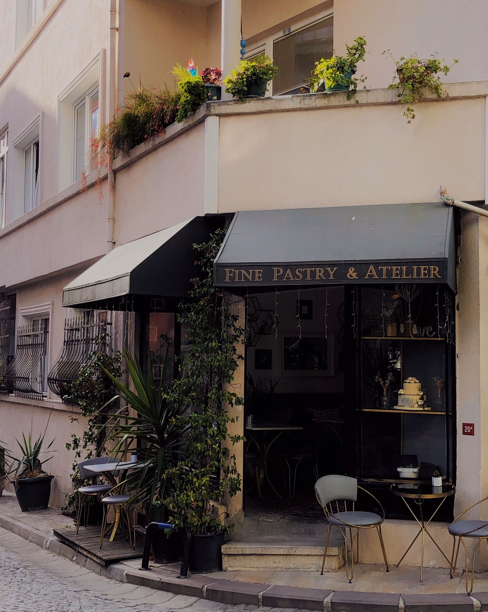 Façade d'une pâtisserie de quartier avec store et terrasse