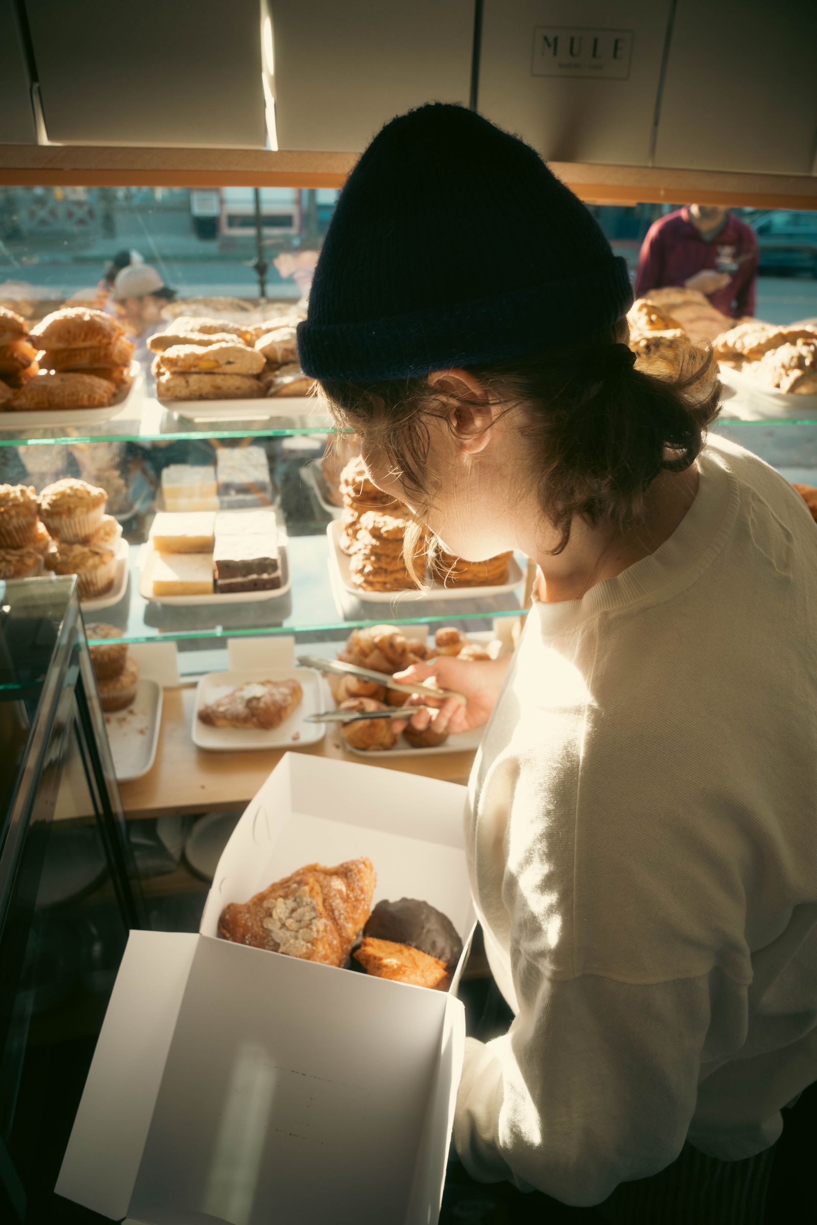 Cliente récupérant sa boîte de pâtisseries en boutique