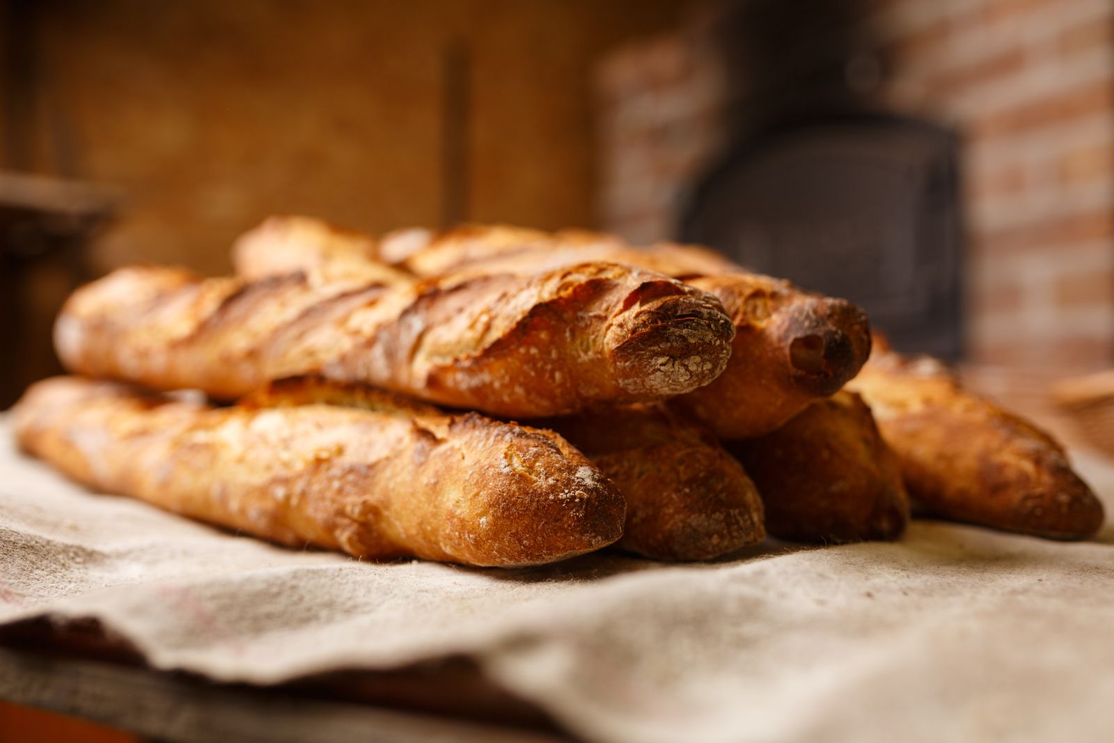 Baguettes sorties du four devant un four à pain en briques
