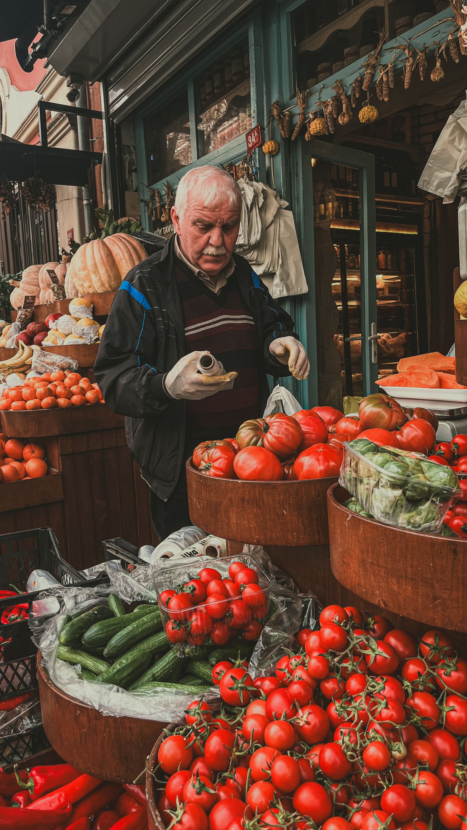 Primeur derrière son étal de tomates et légumes de saison