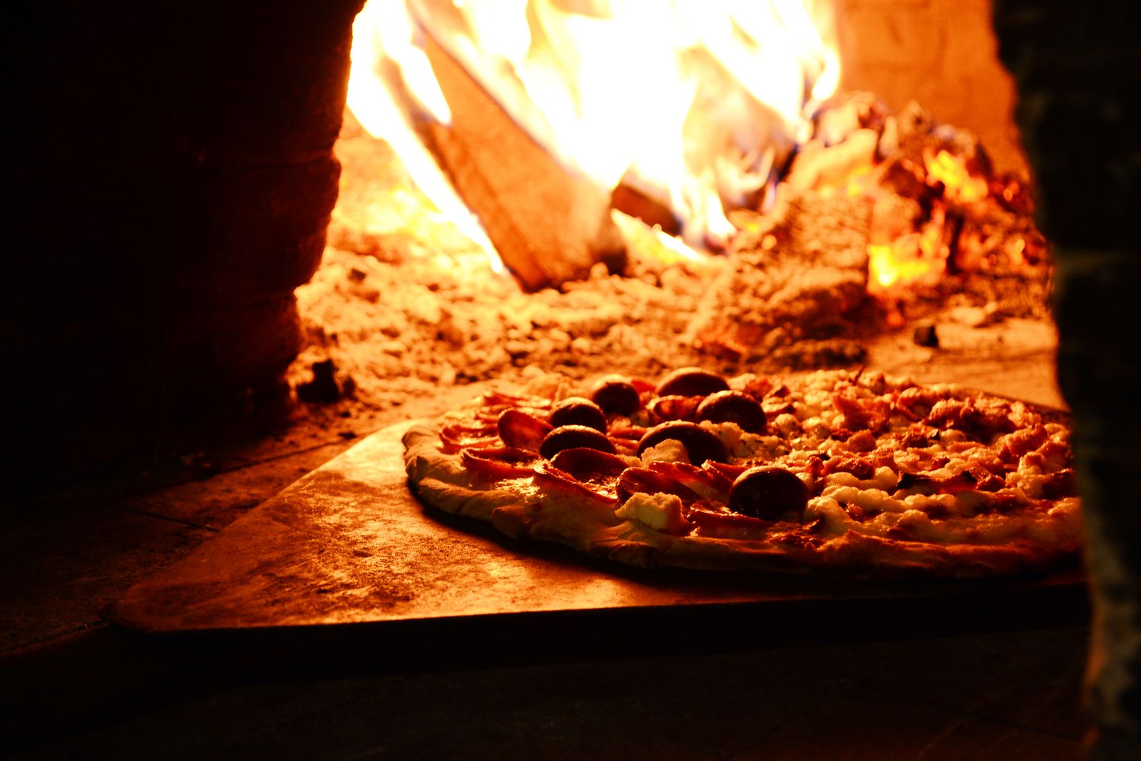 Pizza enfournée dans un four à bois